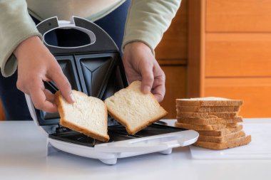 Eller sandviçler için toster 'a iki dilim ekmek koyun.