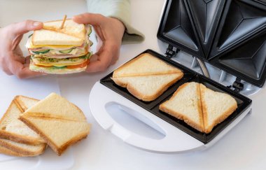 Eller taze peynirli, pastırmalı ve sebzeli taze sandviçi beyaz masanın üstünde tutsun..