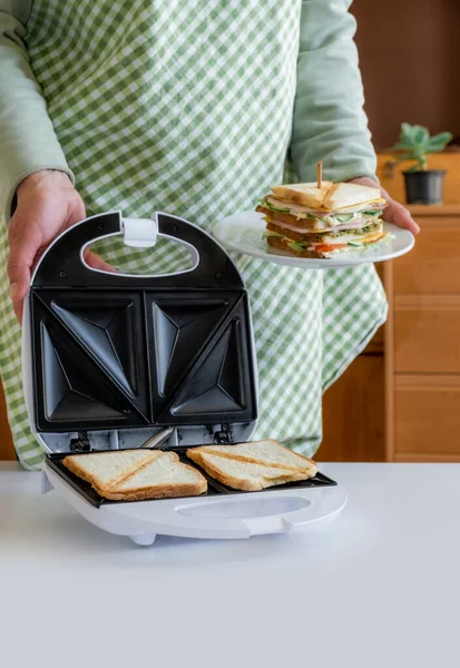 Eller taze peynirli, pastırmalı ve sebzeli taze sandviçi beyaz masanın üstünde tutsun..