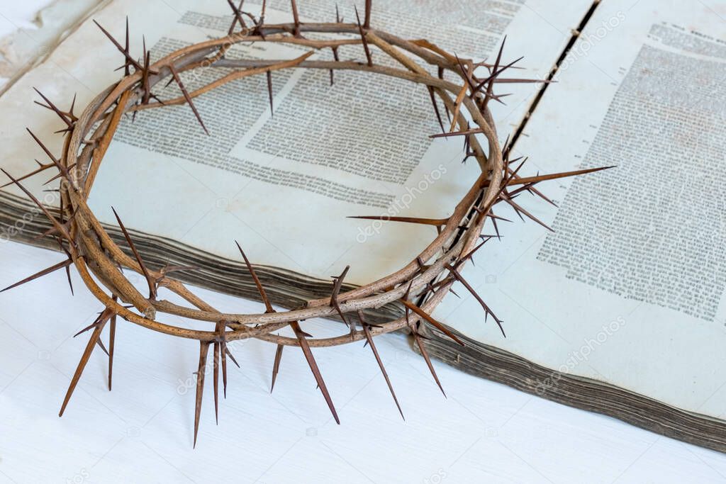 Crown thorns and old bible or book on the white background, copy space.