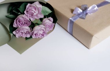 Beyaz arkaplanda hediye kutusu olan menekşe güllerinden bir buket, üst manzara, boşluğu kopyala.