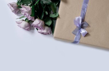 Beyaz arkaplanda hediye kutusu olan menekşe güllerinden bir buket, üst manzara, boşluğu kopyala.