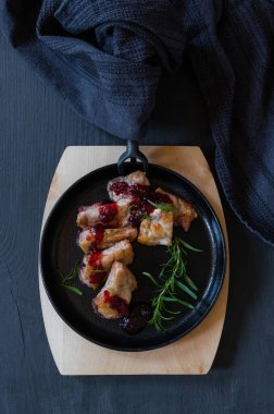 Siyah ya da mavi arka planda kızarmış domuz eti olan dökme demir siyah yuvarlak tava..