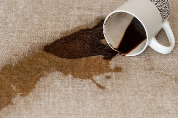 Spilled cup of coffee on the sofa with dirty stain.