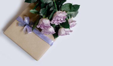 Beyaz arkaplanda hediye kutusu olan menekşe güllerinden bir buket, üst manzara, boşluğu kopyala.