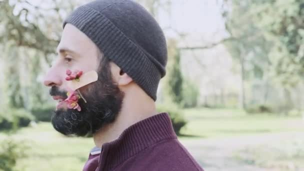男は春の花と彼の顔に医療用接着剤でカメラを見て — ストック動画