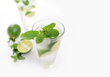 Kokteyl Cin Toniği ya da bardakta mojito. Beyaz arka planda nane, buz, limon..