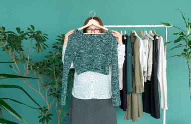 Orta yaşlı kadın alışveriş yapıyor ve rafın yanındaki elbiseye bakıyor..