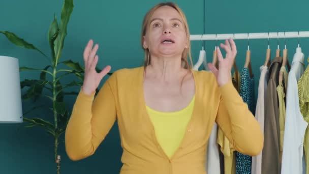 Medelålders Blond Woman Står Nära Hyllan Med Kläder Tittar Kameran — Stockvideo