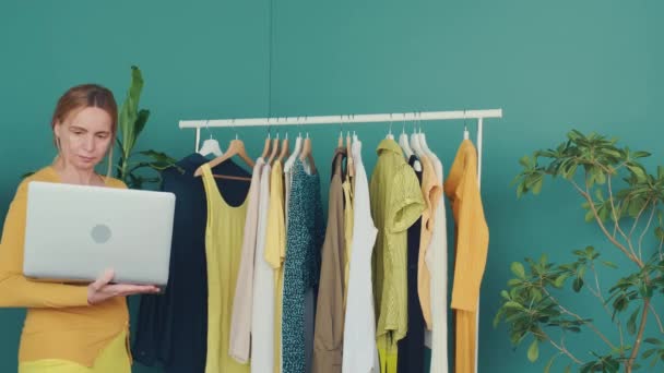 Middle Aged Blond Woman Communicates Online Laptop Shows Clothes Shelf — Stock Video