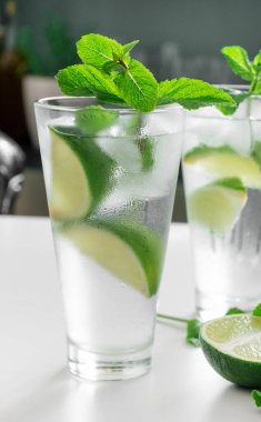 Kokteyl Cin Toniği ya da bardakta mojito. Beyaz arka planda nane, buz, limon..