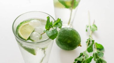 Kokteyl Cin Toniği ya da bardakta mojito. Beyaz arka planda nane, buz, limon..