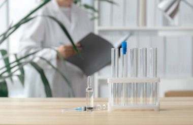 Doktor test tüpleri, ampul ve şırınga ile masanın yanında duruyor. Küresel aşı kavramı..