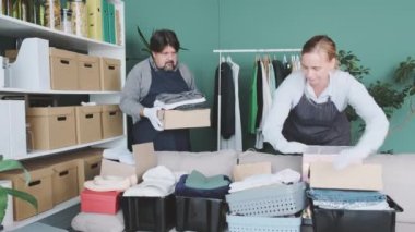 Erkekler ve kadınlar yardım ve bağışta bulunmak için giysi ve ürünleri kutulara koyuyorlar..