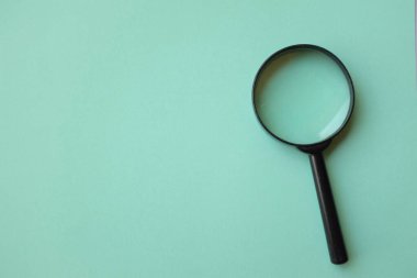 Üst ve düz büyüteç üzerinde yeşil pastel arkaplan üzerinde yatıyordu