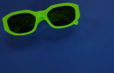 Modern yeşil güneş gözlükleri mavi bir arka planda izole edilir. Gezgin ve yaz aksesuarları.