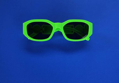 Modern yeşil güneş gözlükleri mavi bir arka planda izole edilir. Gezgin ve yaz aksesuarları.