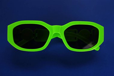 Modern yeşil güneş gözlükleri mavi bir arka planda izole edilir. Gezgin ve yaz aksesuarları.