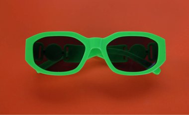 Çağdaş yeşil güneş gözlüklerini kapat turuncu bir arka planda izole et. Gezgin ve yaz aksesuarları.