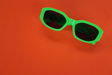 Çağdaş yeşil güneş gözlüklerini kapat turuncu bir arka planda izole et. Gezgin ve yaz aksesuarları.