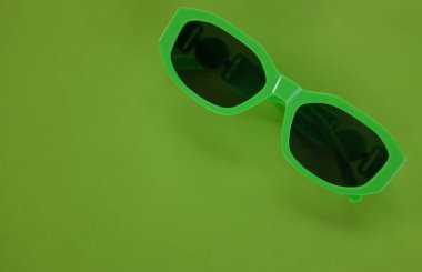 Modern yeşil güneş gözlükleri yeşil bir arka planda izole edilir. Gezgin ve yaz aksesuarları.