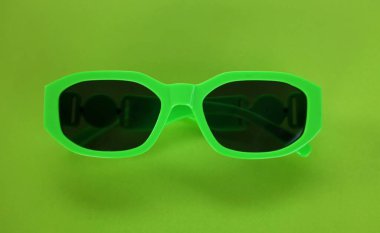 Modern yeşil güneş gözlükleri yeşil bir arka planda izole edilir. Gezgin ve yaz aksesuarları.