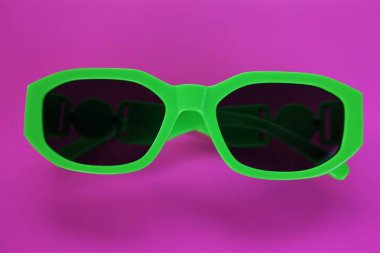 Modern yeşil güneş gözlükleri pembe bir arka planda izole edilir. Gezgin ve yaz aksesuarları.