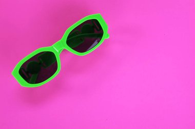 Modern yeşil güneş gözlükleri pembe bir arka planda izole edilir. Gezgin ve yaz aksesuarları.