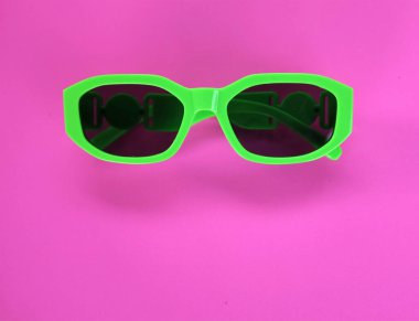 Modern yeşil güneş gözlükleri pembe bir arka planda izole edilir. Gezgin ve yaz aksesuarları.