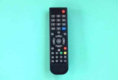 Üst ve düz televizyon uzaktan kumandası yeşil pastel arka planda. TV izleme kavramı.