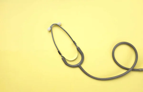 top view A stethoscope on a yellow doctor table, concept of health and medicine