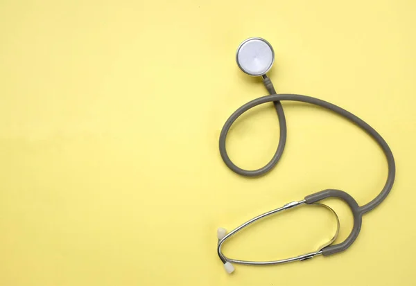 top view A stethoscope on a yellow doctor table, concept of health and medicine