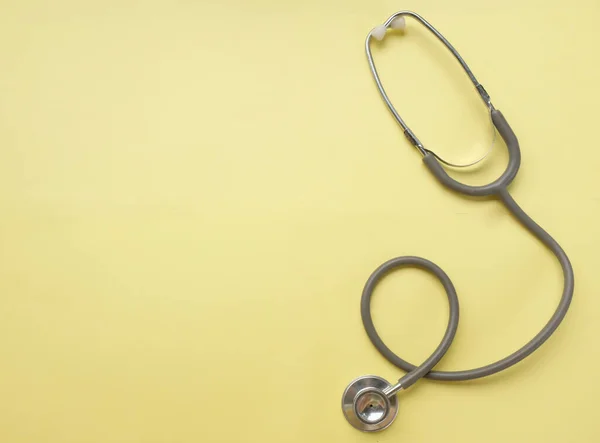 A stethoscope on a yellow doctor table, concept of health and medicine