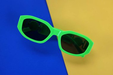 Modern siyah güneş gözlükleri sarı ve mavi arka planda izole edildi. Gezgin ve yaz aksesuarları.