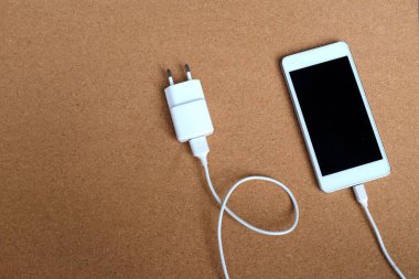 Kahverengi Arkaplanda Akıllı Telefon ile Şarj Bağlantısını Kapat.