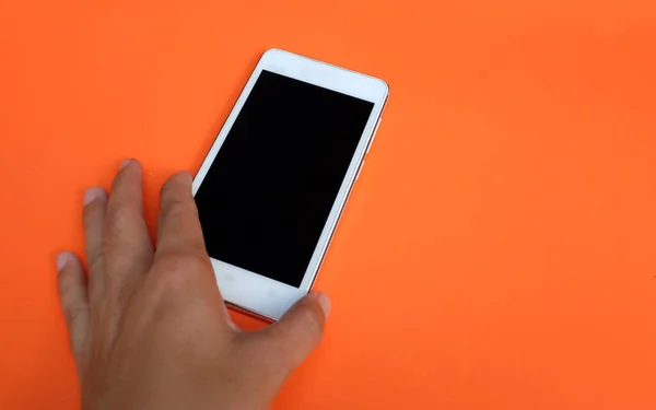 modern smartphone with blank screen for mockup in woman\'s hands on orange background. copy space