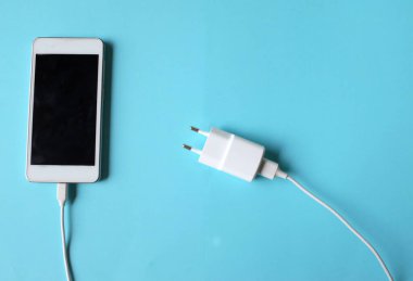 Close up and top view Smartphone Connects with Charger on blue Background 