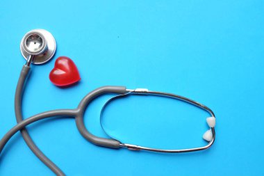 Mavi bir doktorun masasına steteskop ve kırmızı bir kalp koyun. Sağlık hizmetleri doktorunun ofisi kavramı.