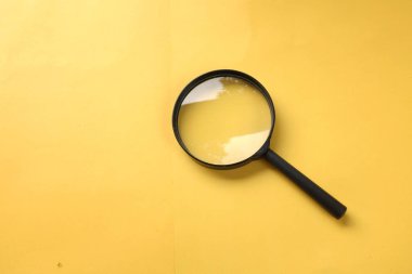 Büyüteç, sarı bir arkaplanda izole edilmiş. Arama sembolü ve genişleyen berraklık.