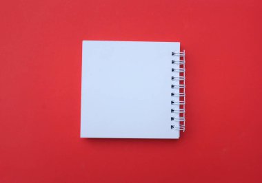 düz ve üst görünüm boş beyaz spiral not defteri bir masa kırmızı arka plan üzerinde. Eucation ve iş kavramı