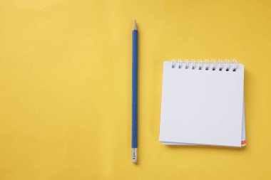 Beyaz spiral not defterine sarı masa arkaplanındaki uzay kalemini kopyala