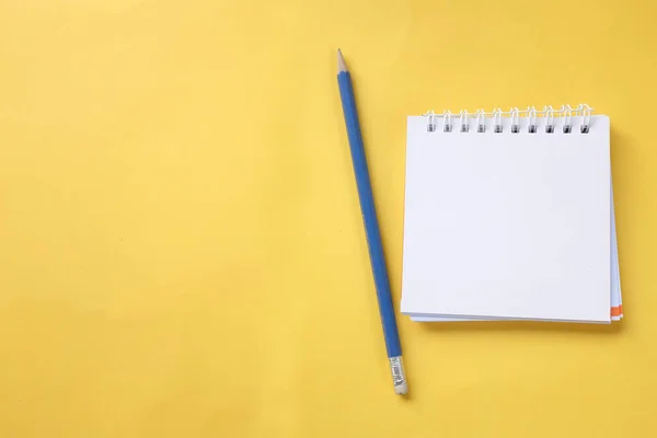 Beyaz spiral not defterine sarı masa arkaplanındaki uzay kalemini kopyala