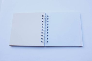 Üst ve düz uzanan boş boş boş sarmal not defteri beyaz bir arkaplanda izole edilir. Ofis veya eğitim ekipmanları.