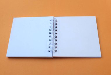 Latty Blank açık beyaz spiral not defteri turuncu bir arka plana izole edildi. Ofis ya da eğitim ekipmanları.