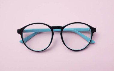 Üst ve düz siyah göz gözlükleri uzanmış pembe pastel arka planda izole edilmiş.