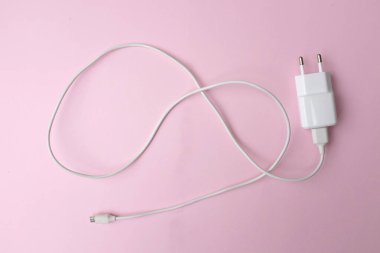 Üst görünüm ve düz konum şarj adaptörü Pembe pastel arka plan üzerinde beyaz akıllı telefon rengi