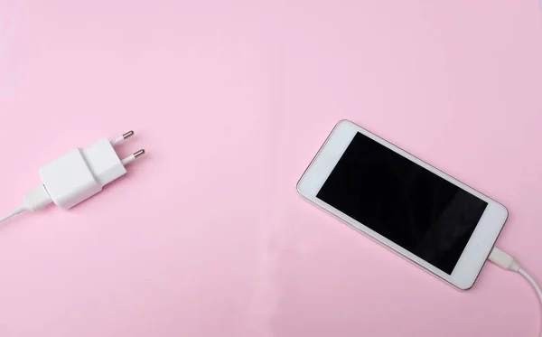 top view and flat lay white Smartphone Plug In with Charger Adapter on pink pastel Background