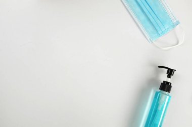 Beyaz zemin üzerinde bakteri ve koronavirüs için kopyalama alanı ve düz yüz maskesi ve Alkol jeli dezenfektan el jeli temizleyiciler