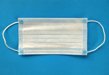 Bir koronavirüsü önle. Tıbbi maske, mavi arka planda izole edilmiş.