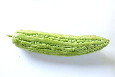 Düz bir zemin üzerinde iki taze yeşil sebze uzanıyordu. Acı kabak ya da acı kavun beyaz bir zemin üzerinde izole edilmiş.